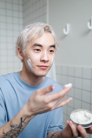 man applying face lotion